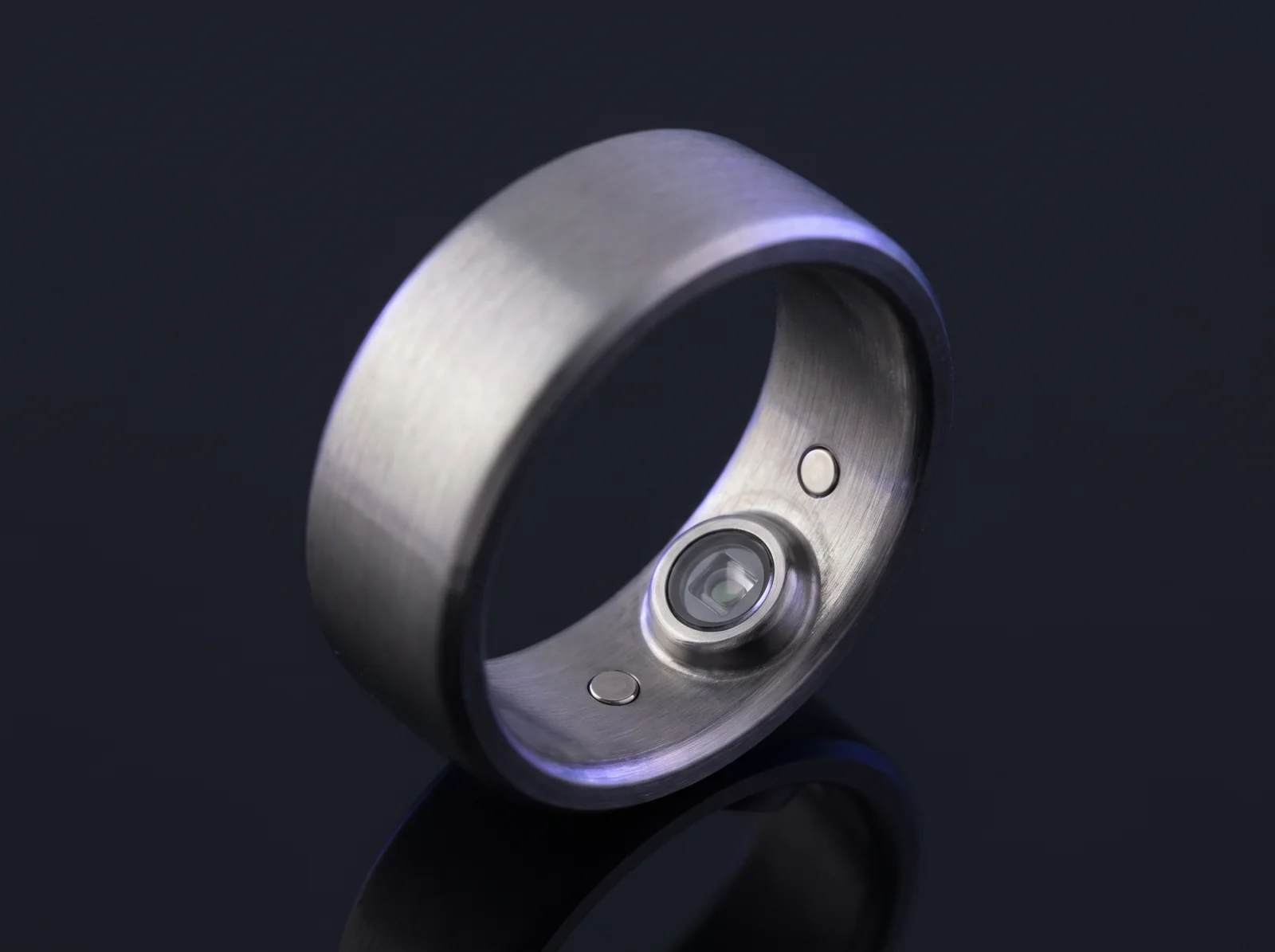 Concept render of a titanium smart ring turned to show the optical heart-rate sensor window on its inner surface