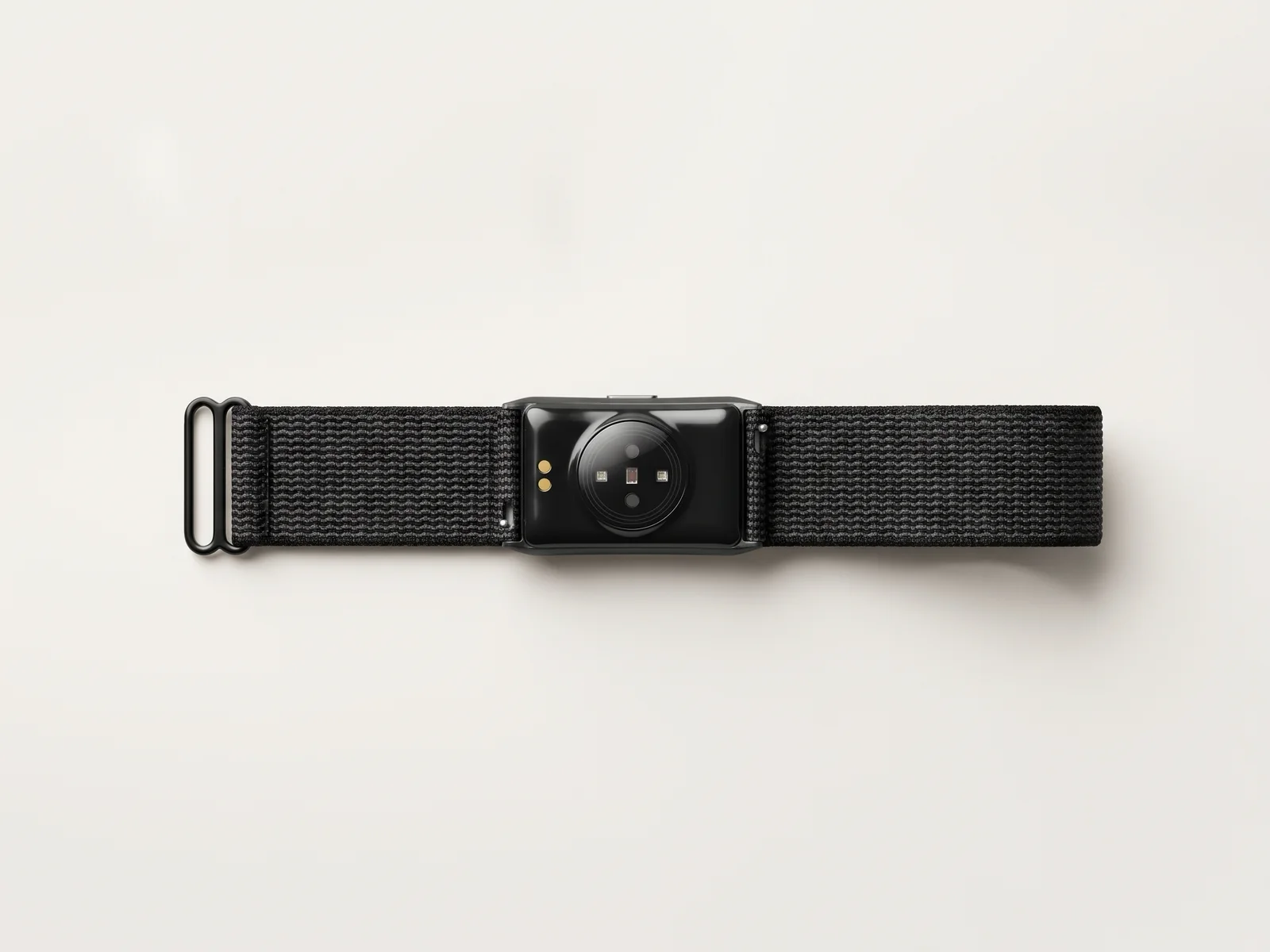 Product render of the slim band from below: a circular optical heart-rate sensor window and two magnetic charging contacts